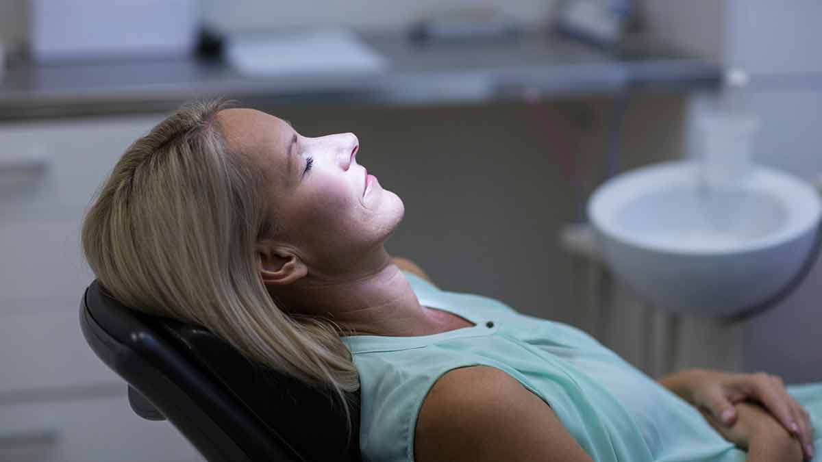 sedation - photo features a women laying back on a dental chair comfortable sedation dentistry.